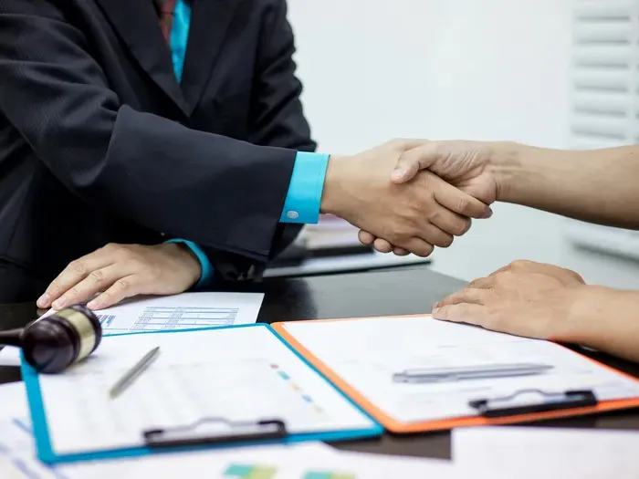 Two people shaking hands over paperwork at an office desk, highlighting business services and trusted listings
